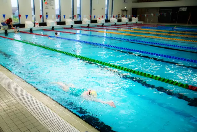 A swimmer cutting smoothly through the water in a designated pool lane.